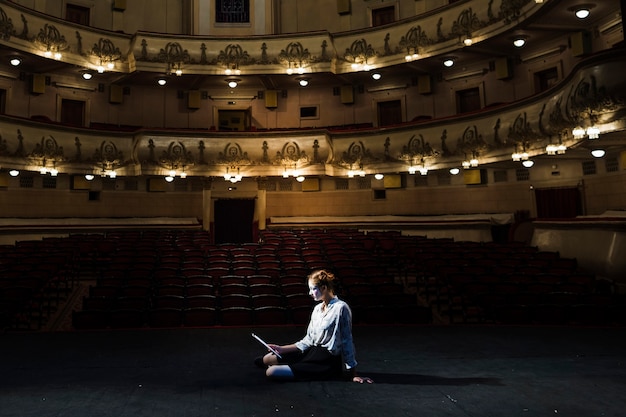 Mime manuscrito de lectura en el escenario en el auditorio vacío