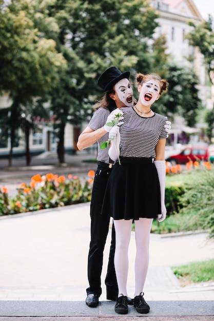 Mime masculino asustando mimo femenino en el parque