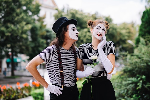 Mime masculino mirando mimo femenino feliz en el parque