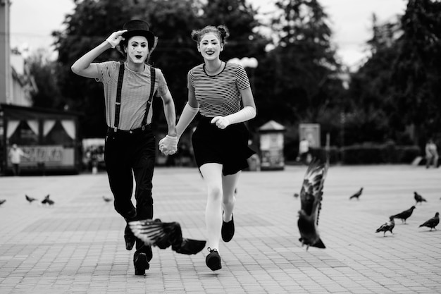 Mime pareja cogidos de la mano corriendo sobre el pavimento