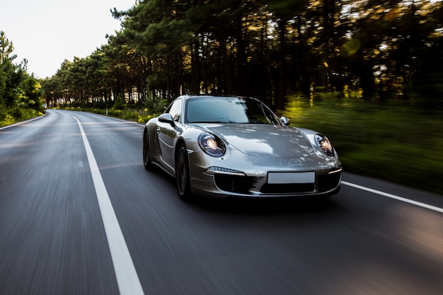 Mini coupé de alta velocidad en carretera con luces delanteras encendidas.