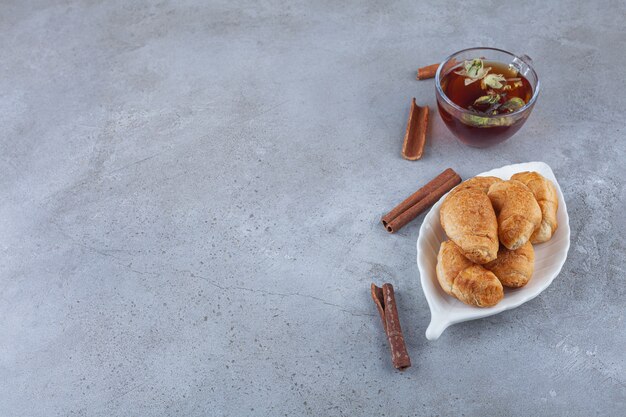 Mini croissants de hojaldre con costra dorada y una taza de té.