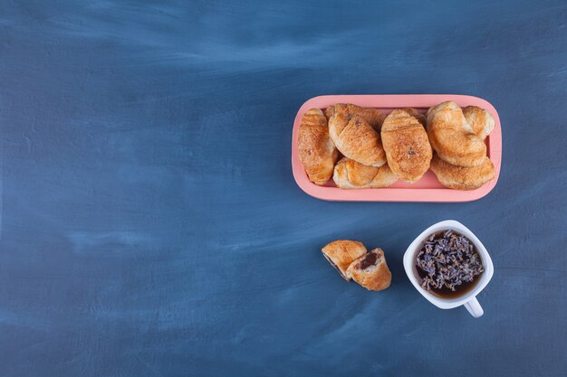 Mini croissants de hojaldre con costra dorada y una taza de té.