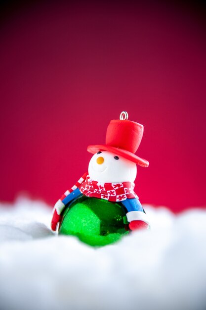 Mini muñeco de nieve de vista frontal sobre fondo rojo.