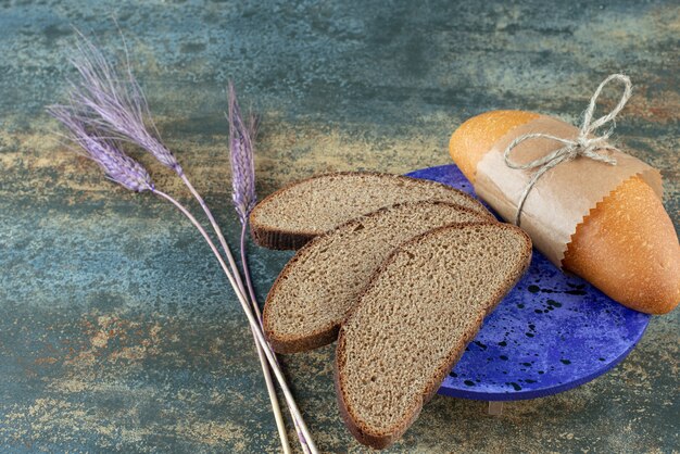 Mini pan blanco con rebanadas de pan integral fresco en placa azul