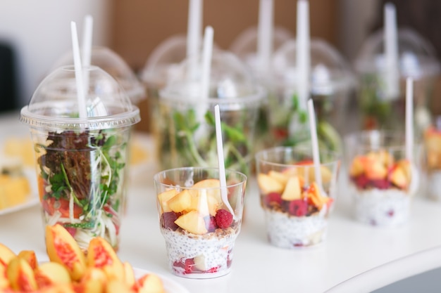 Mini postres y ensaladas de vegetales sanos y vegetales en canapés de vasos de plástico.