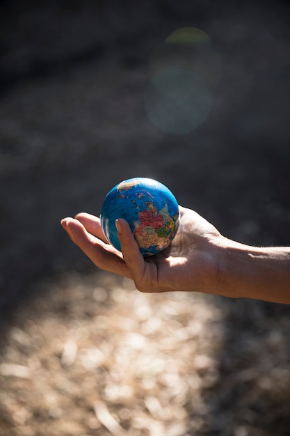 Miniatura globo en mano en la naturaleza