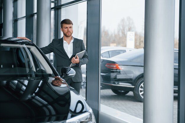 Mira lejos. Empresario barbudo con estilo moderno en el salón del automóvil