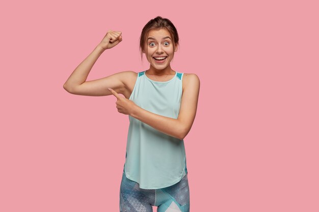 ¡Mira lo fuerte que soy! Mujer joven alegre con amplia sonrisa