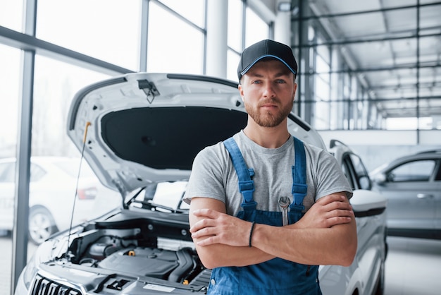 Mirada seria. Empleado en el uniforme de color azul se encuentra en el salón del automóvil