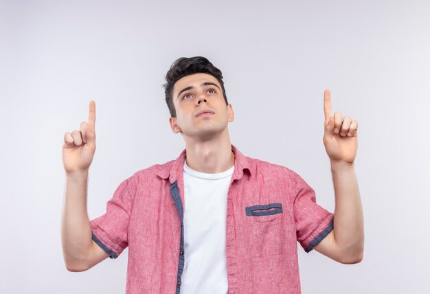 Mirando hacia arriba caucásico joven vistiendo camisa rosa apunta hacia arriba sobre fondo blanco aislado