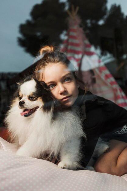 Mirando fuera de la ventana niña y cachorro esponjoso