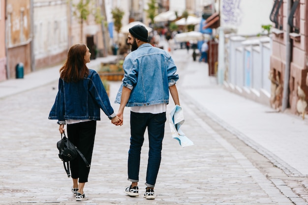 Mire por detrás a la pareja de turistas que se dan la mano mientras caminan por la ciudad