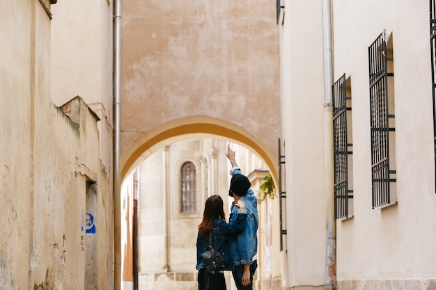 Mire por detrás a la pareja de turistas que ven algo mientras pasean por la ciudad