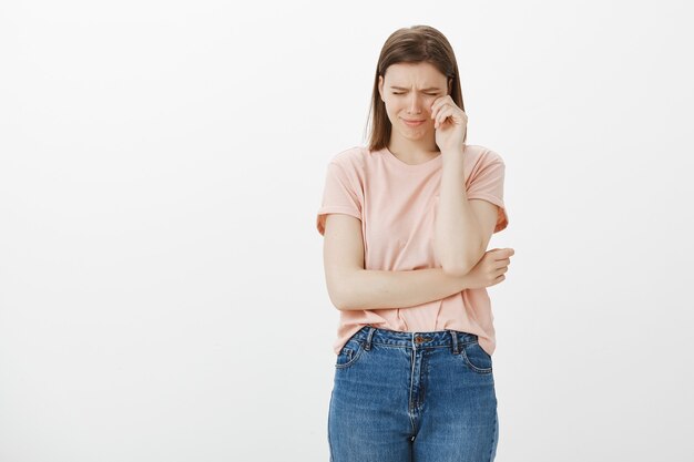 Miserable y triste mujer linda llorando, sollozando y sintiéndose molesta, secándose las lágrimas