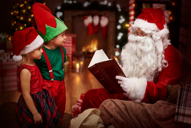 Misterioso santa claus leyendo un libro con niños