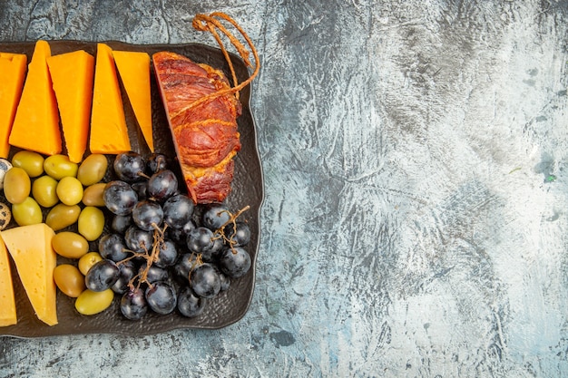 La mitad de la foto del delicioso mejor aperitivo para el vino servido en una bandeja marrón en el lado derecho sobre fondo gris