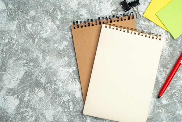 La mitad de la foto de dos cuadernos de espiral kraft con bolígrafos de colores sobre fondo de hielo