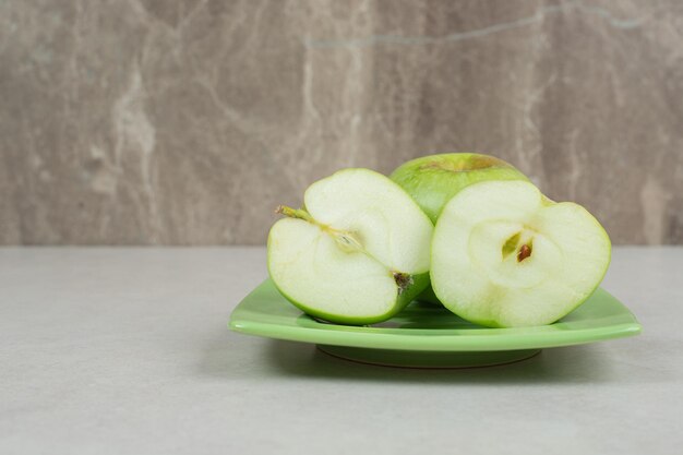 Mitad de manzanas verdes cortadas en placa verde.