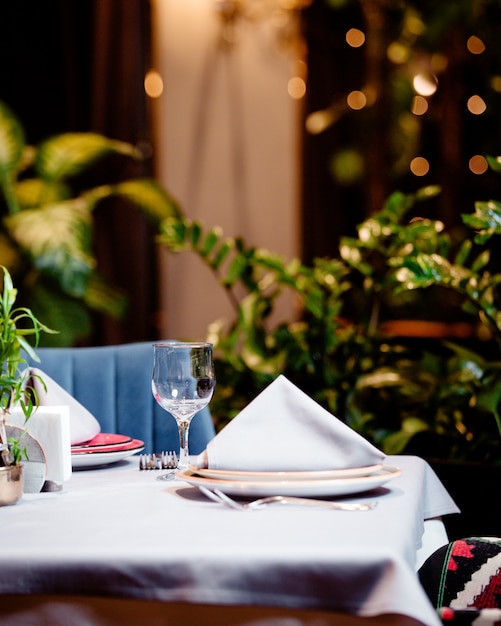 La mitad de la mesa de restaurante vacía con plato de cristal y cubiertos.