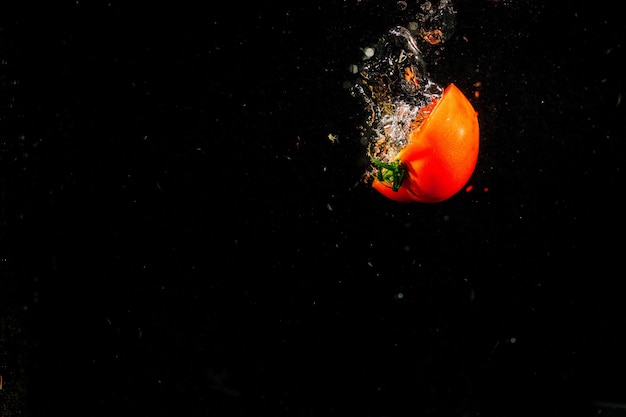 La mitad de tomate cae sobre fondo negro