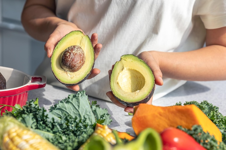 Foto gratuito las mitades de aguacate en una mano femenina en la cocina