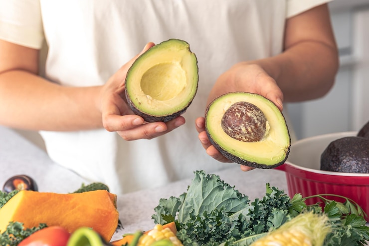 Foto gratuito las mitades de aguacate en una mano femenina en la cocina