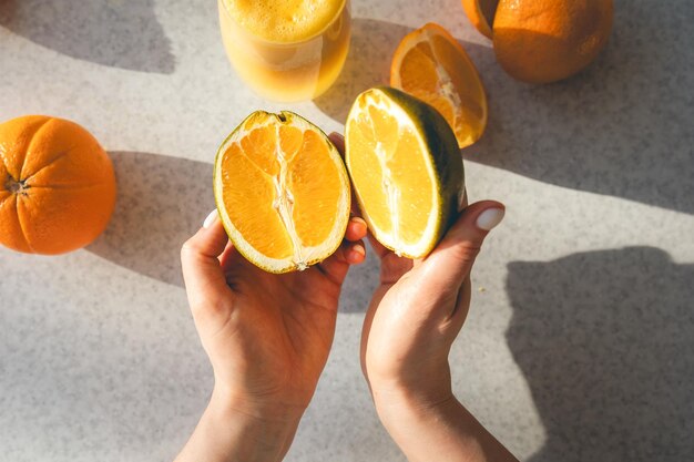 Foto gratuita mitades de una naranja fresca en manos femeninas en el fondo de la mesa de la cocina
