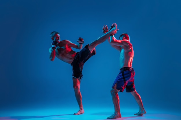 MMA. Dos luchadores profesionales de perforación o boxeo aislado en la pared azul en neón