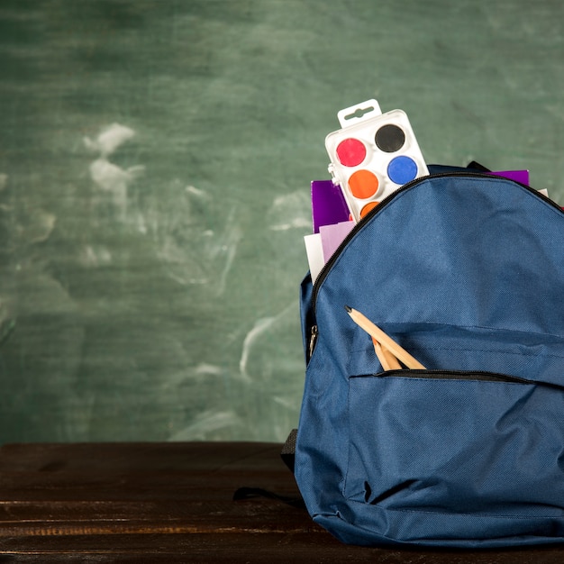 Mochila azul con papelería y acuarelas.