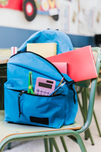 Mochila con papelería en silla.