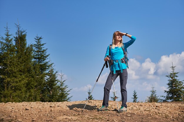 Mochilero rubio femenino que camina en el camino de piedra