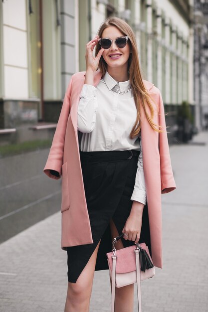 Moda atractiva elegante mujer rica sonriente caminando calle de la ciudad en abrigo rosa