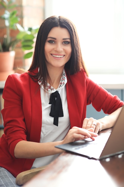 Moda joven mujer morena trabajando desde casa con ordenador portátil. concepto de teletrabajo