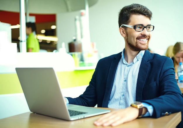 Moda joven sonriente hombre hipster en el café de la ciudad durante la hora del almuerzo con cuaderno en traje