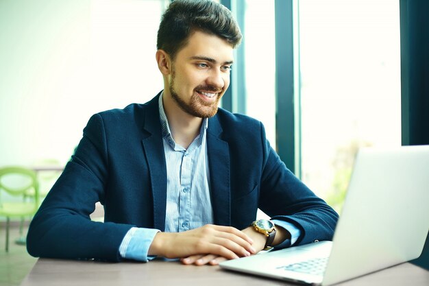 Moda joven sonriente hombre hipster en el café de la ciudad durante la hora del almuerzo con cuaderno en traje