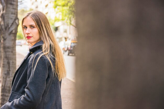 Moda joven vestida mujer de pie en la calle urbana