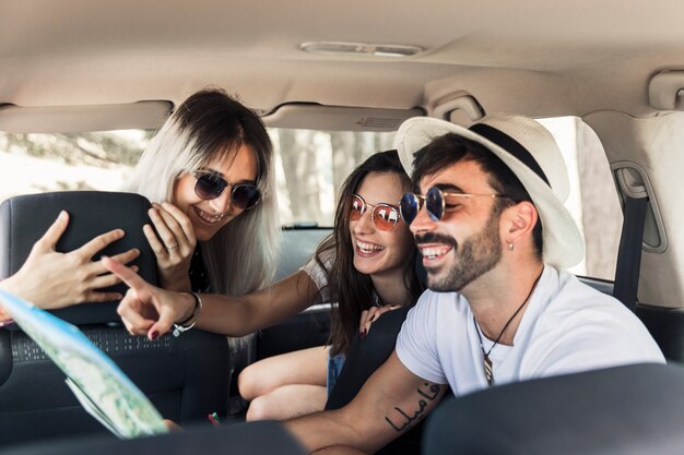 Moda jóvenes amigos sentados dentro del coche moderno mirando el mapa