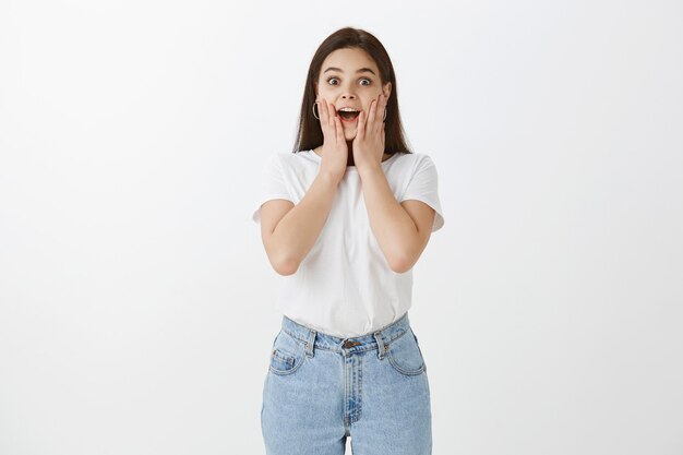 Moda mujer joven emocionada posando contra la pared blanca