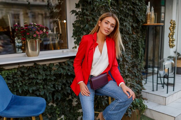 Moda mujer rubia caucásica en elegante chaqueta roja disfrutando de fin de semana en el café