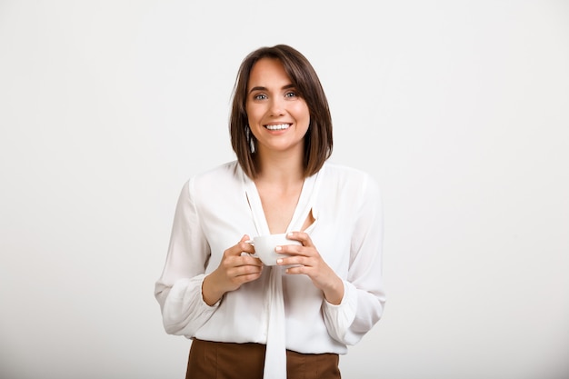 moda mujer tomando café en la oficina, sonriendo feliz