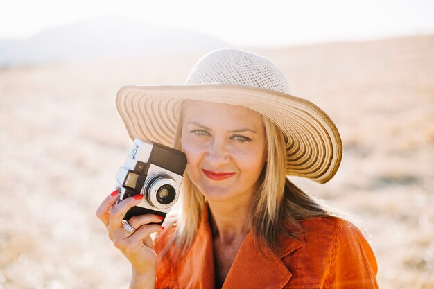 Modelo adulto con cámara vieja en la naturaleza