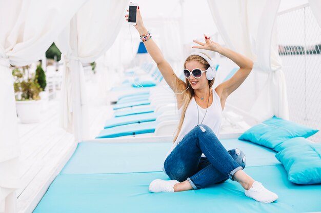 Modelo alegre posando con gadgets en verano