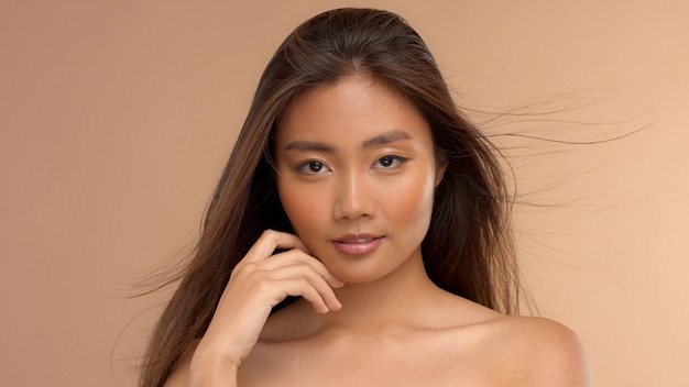Modelo asiático tailandés con maquillaje natural sobre fondo beige