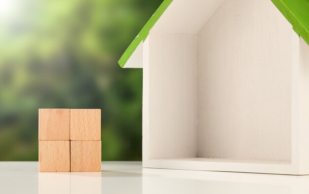 Modelo de caja de casa y cubos de madera sobre una superficie blanca - concepto de negocio inmobiliario