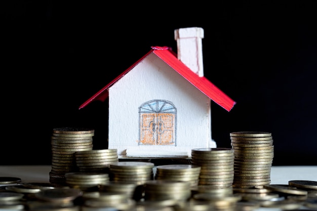 Modelo de casa con monedas en mesa de madera.