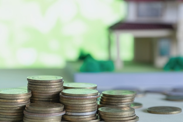 Foto gratuita modelo de casa con monedas en mesa de madera.