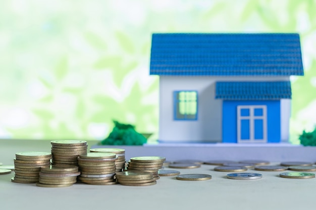 Modelo de casa con monedas en mesa de madera.