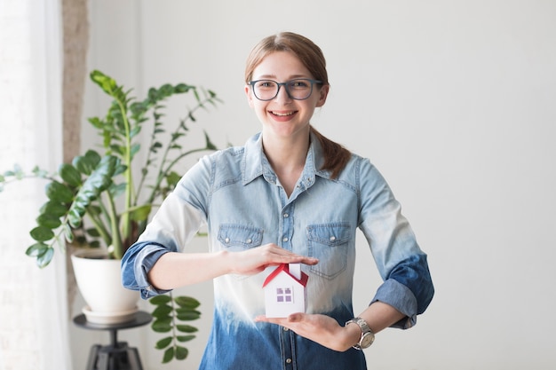 Foto gratuita modelo de casa sonriente de la protección de la mujer en la oficina que mira la cámara