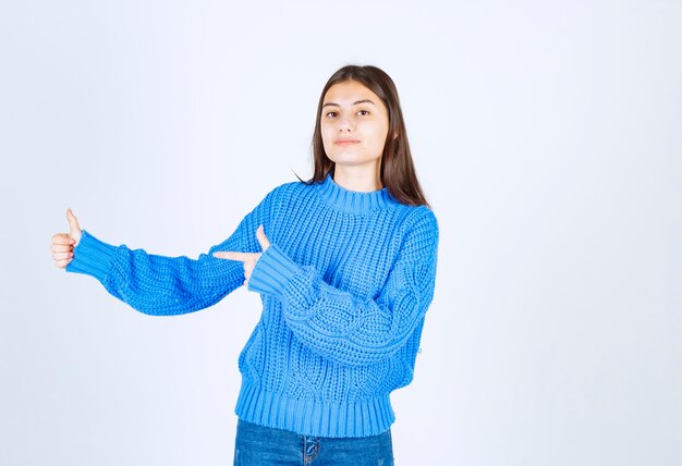 modelo de chica joven apuntando hacia afuera y mostrando un pulgar hacia arriba.